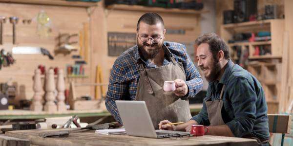 Things To Do When Starting a Craft Business in Indiana 1 Two men in their Indiana-based workshop, smiling as they review the things they must do to start their craft business.