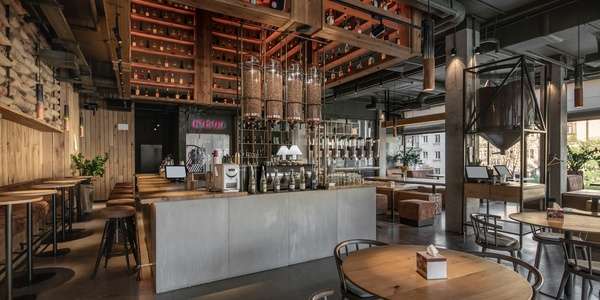 Tips for Decorating Your Restaurant Interior 1 The interior of a loft style restaurant with a bar in the center. It uses wooden surfaces, bar seating, and hanging lights.